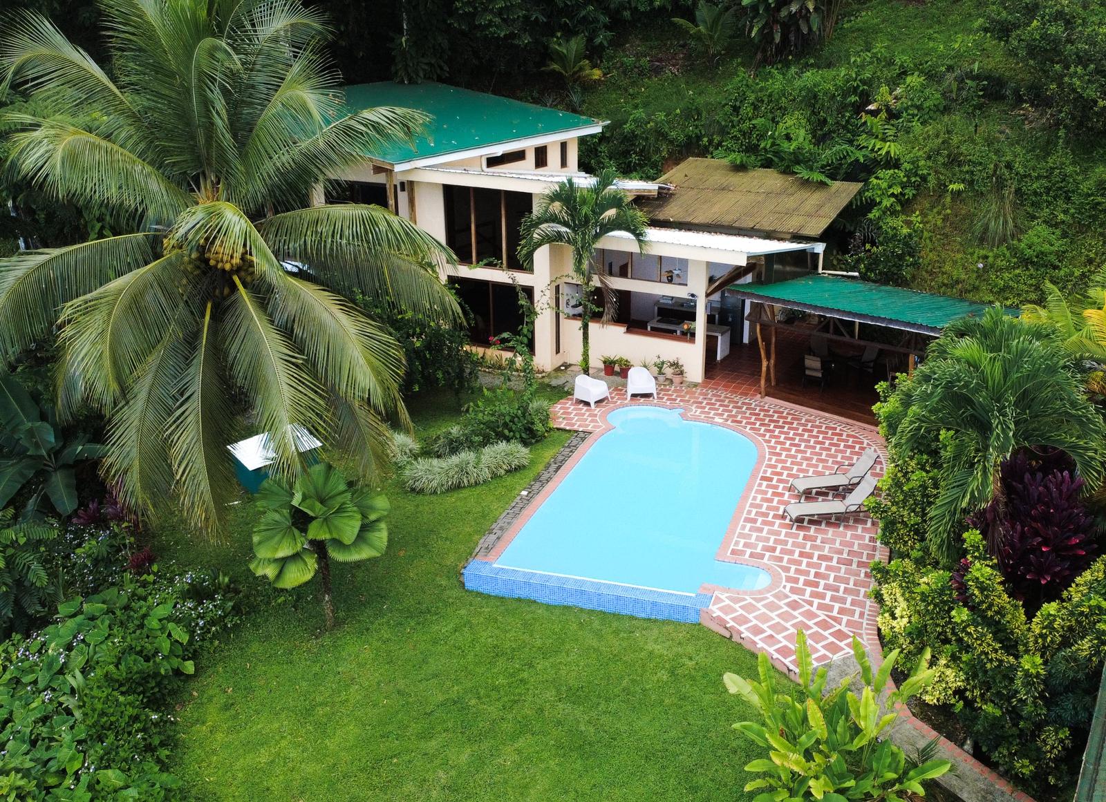 Aerial view of the villa, pool and gardens surrounded by palms