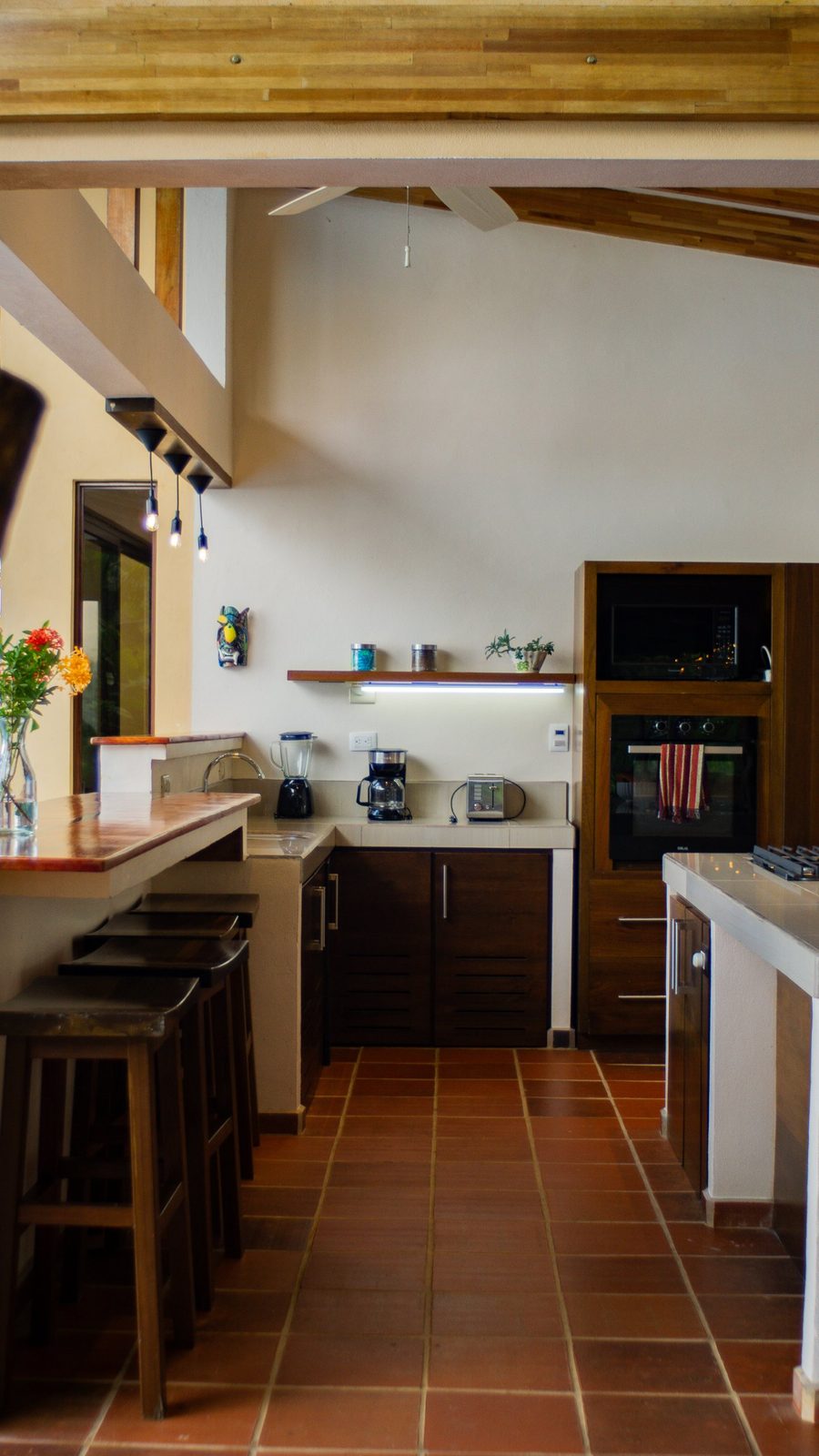Open kitchen with terracotta floors, wood beams and a breakfast bar
