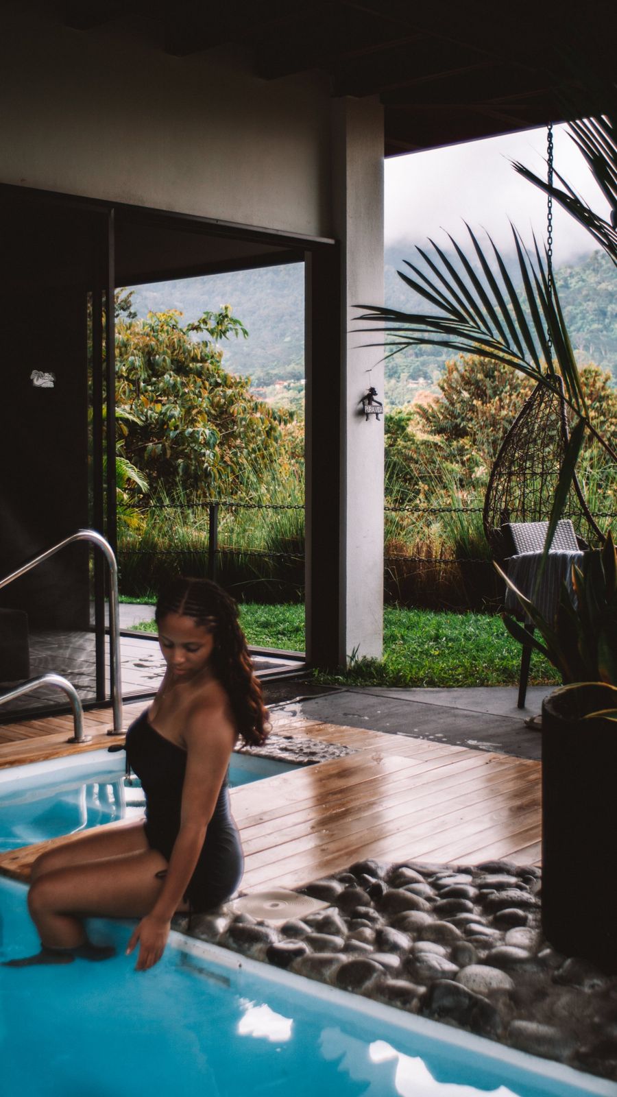Guest dipping a hand into the plunge pool beside the open terrace and mountain view