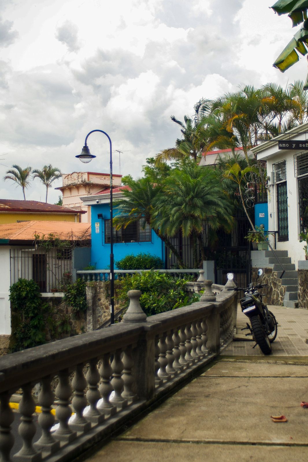 Colorful San Jos&eacute; street with a stone balustrade, palms and a parked motorcycle