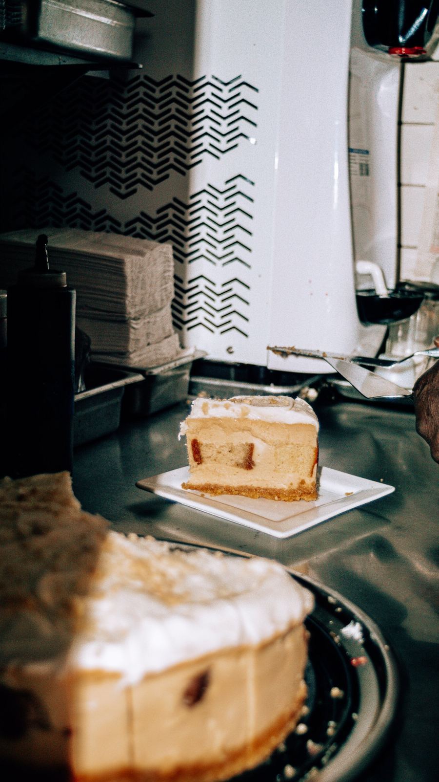 Fresh slice plated at the counter beside the whole cheesecake