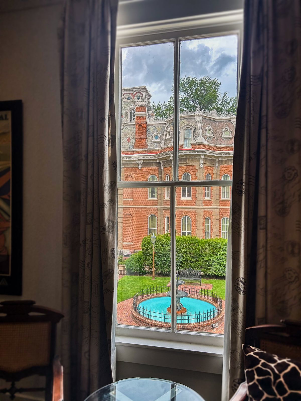 Window view of the Victorian mansion and courtyard fountain