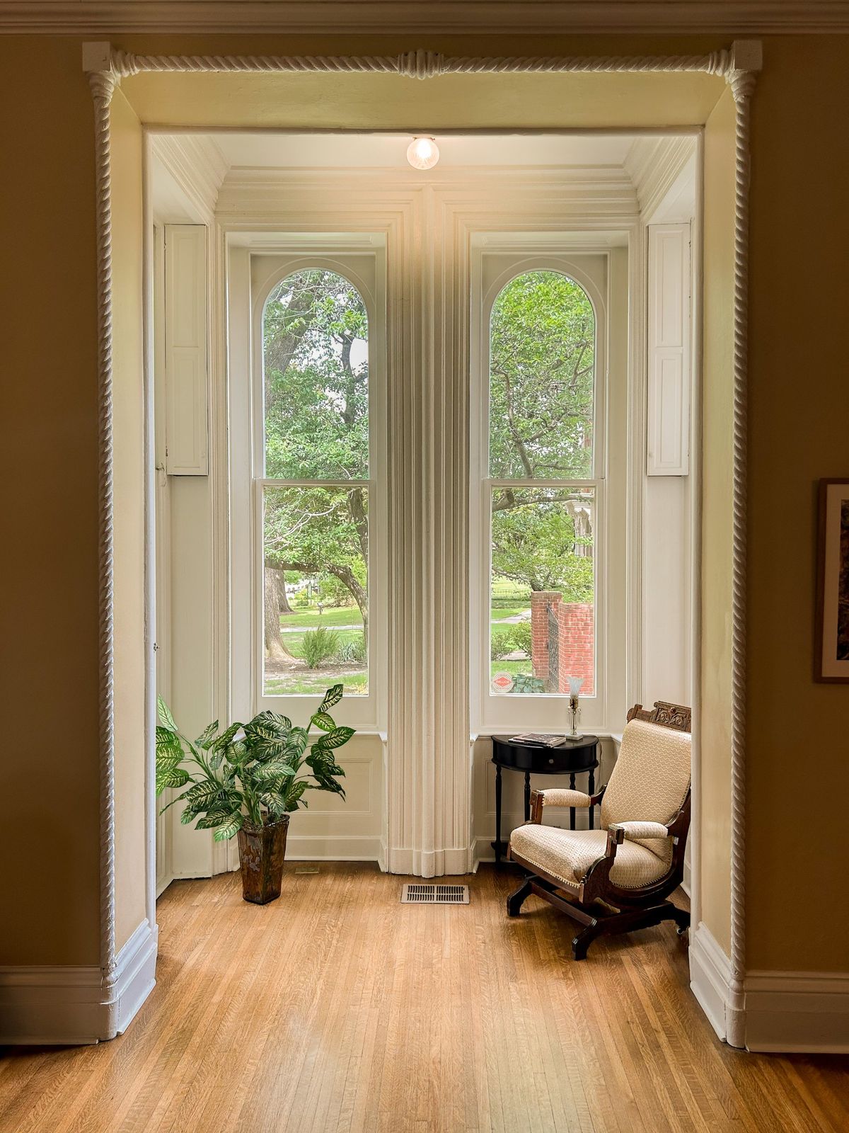 Bay window nook with arched windows, a rocking chair and a plant
