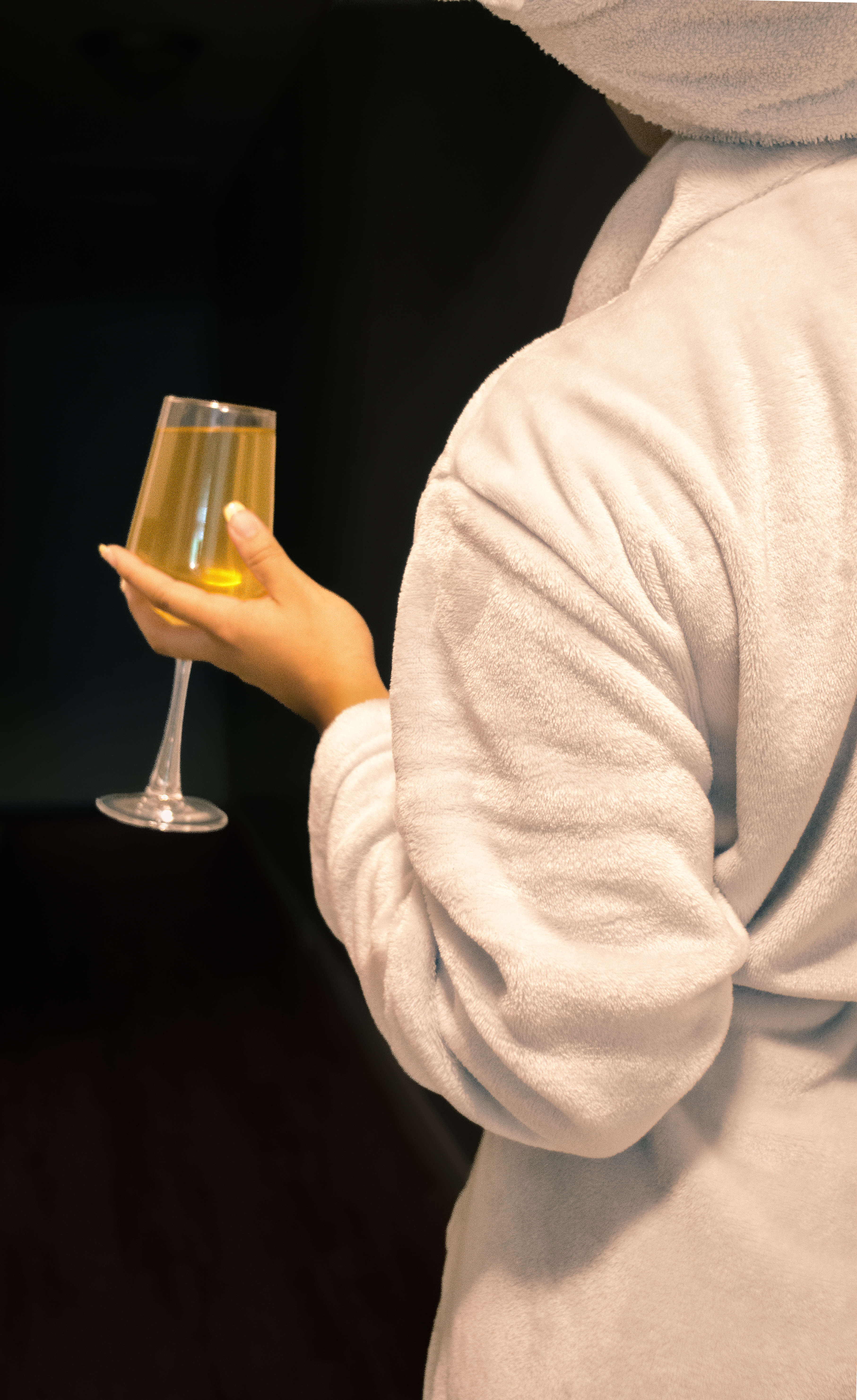 Guest in a plush robe holding a glass of champagne